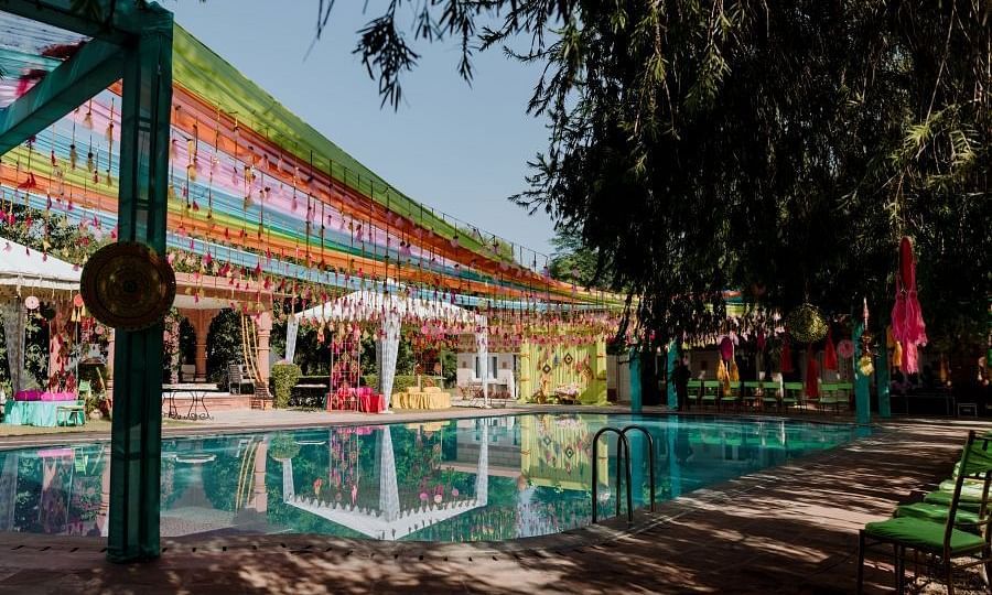 A poolside wedding venue with green foliage covering the shot- Umaid Palace - A Lakeside Heritage Palace Resort
