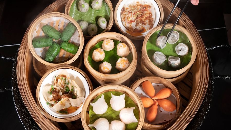 image of a well served steamed dishes that a person is trying to pick using a pair of chopsticks - The Claridges New Delhi