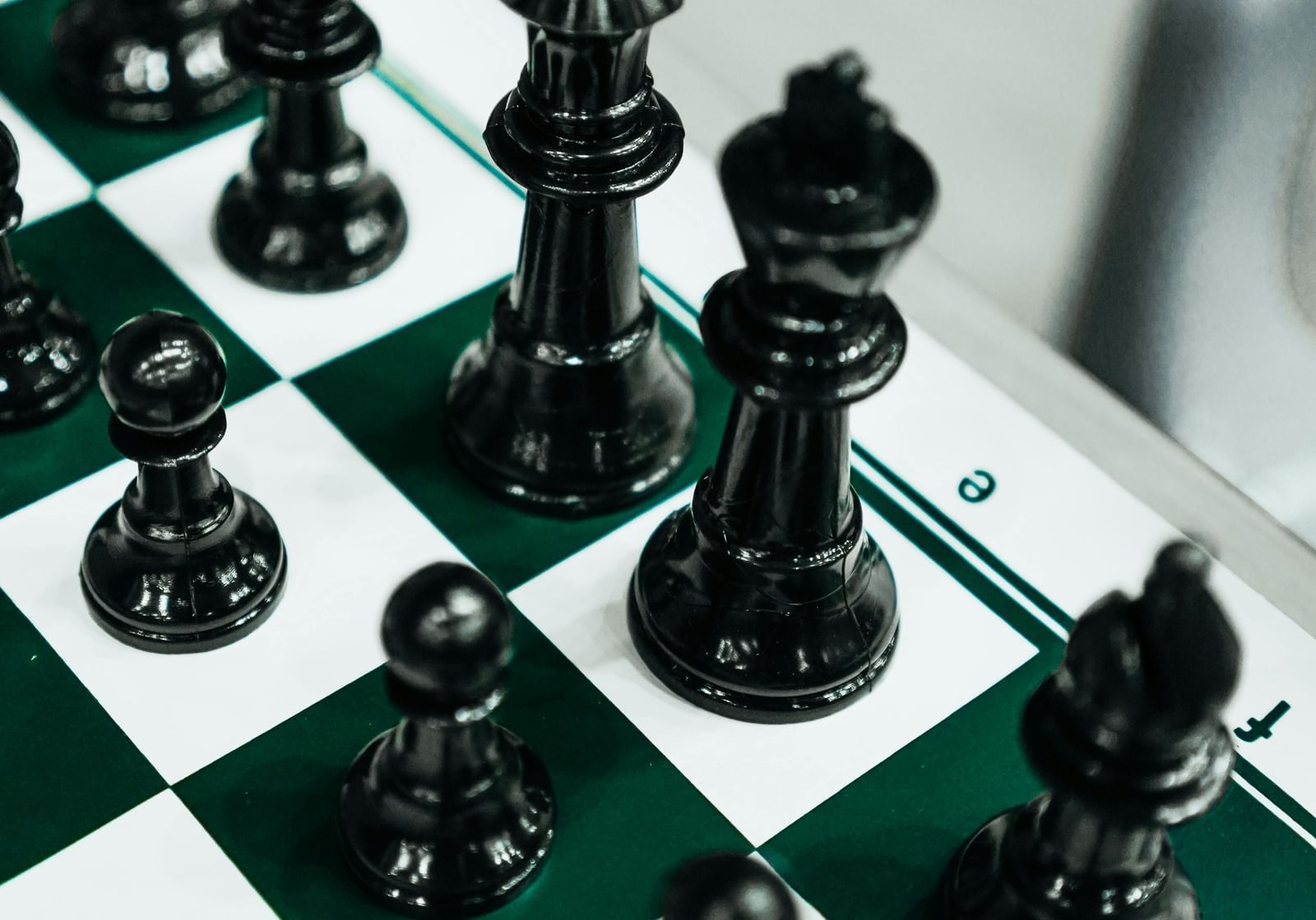 Close-up of a chessboard with neatly arranged black pieces.
