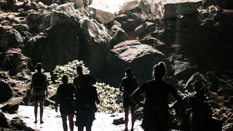 Back shot featuring the silhouette of several tourists leaving a cave.