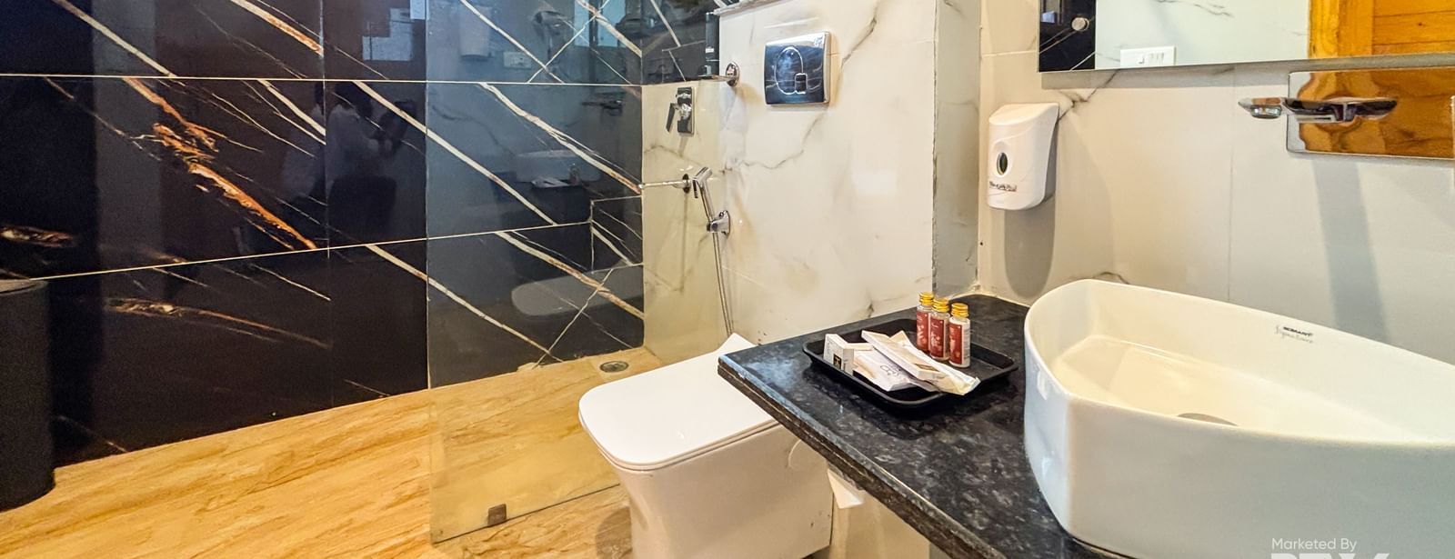 A sleek, modern bathroom featuring dark marble tiles, a white basin sink, and clean lines at Corbett Nirvana Resort.