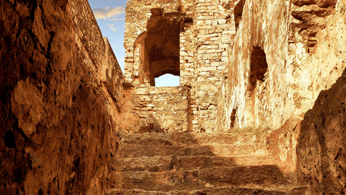 Steps inside a cave leading to the chandragiri fort with dark skies in the background