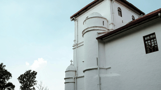 A white building with multiple levels and a tower, photographed from the ground with a clear sky.