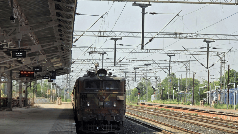 An electric train arrives at a nearly empty railway station under a clear sky, with overhead electric lines visible | Chennai to Pudukkottai train