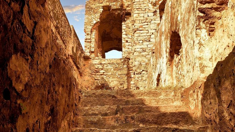 Steps inside a cave leading to the chandragiri fort with dark skies in the background
