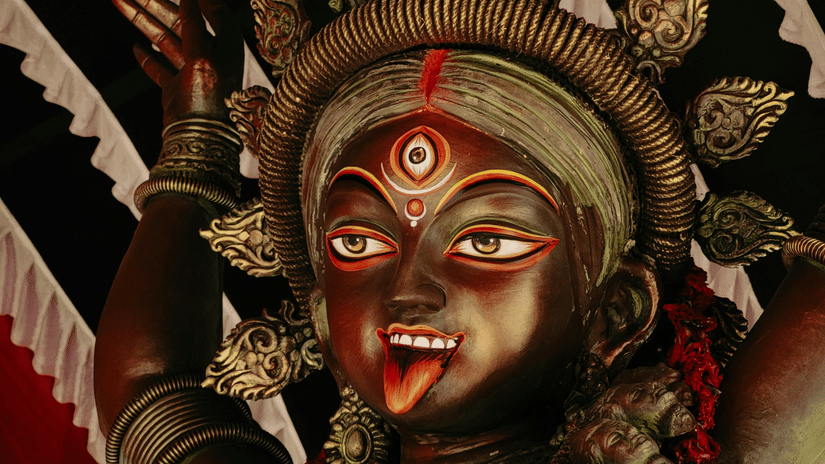 An idol of Indian goddess with decorations in the background