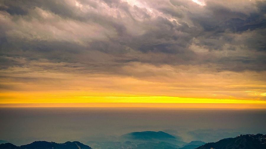 A view of a mountain silhouetted against a vibrant orange-yellow skyline.
