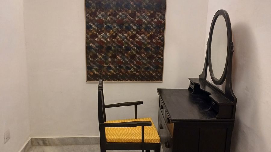 Simple room with dark wooden desk, chair, round mirror, and white marble flooring at Neemrana Fort-Palace.