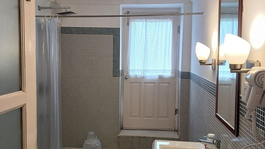 Bathroom with white marble vanity, wall-mounted toilet, and grey floor tiles at Neemrana Fort-Palace.