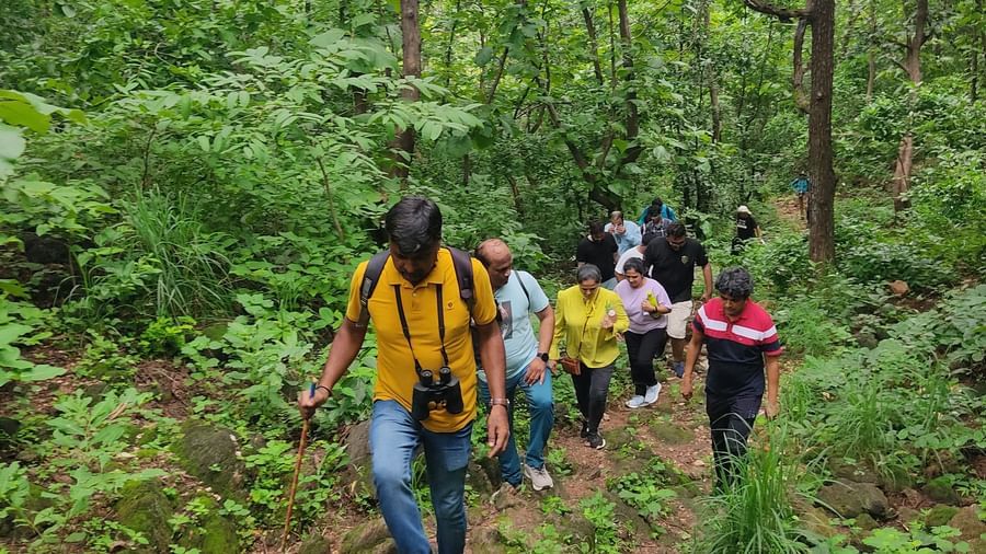 A group of people trekking around the forest area on a narrow rugged path at Daksh Resort and Amusement Park.