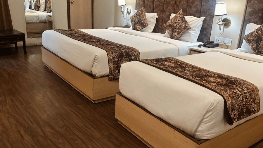 Hotel Exotic, Amritsar features a twin bedroom with wooden flooring, two beds, bedside tables and curtained windows.