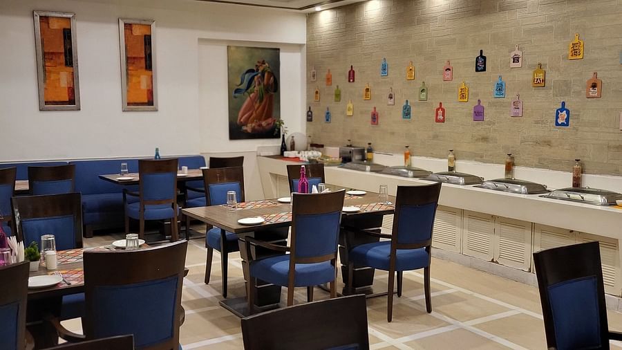 An image of a restaurant featuring multiple sets of chairs and tables where plates, cutlery and napkins are placed at Inde Hotel Signature Tower Gurgaon