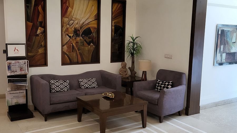 An image of a reception lobby featuring sofa set, centre table, some plants, and photo frames hanged on the wall at Inde Hotel Signature Tower, Gurgaon