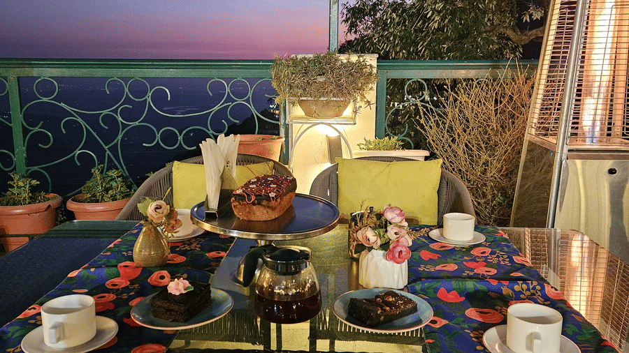 A terrace with tables set for dining under ambient lighting, offering sunset views at Mongas Hotel & Resort, Dalhousie.