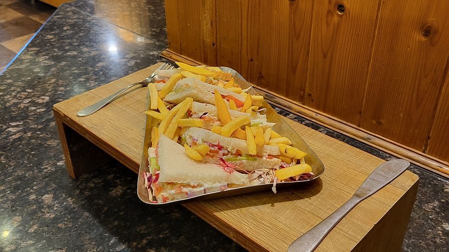 Sandwich on a wooden tray with a knife on the side at Dagshai Manor Kasauli - Inde Hotels.
