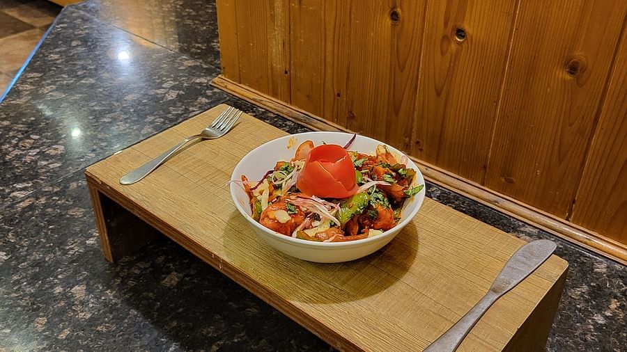 Wooden tray with a salad bowl and cutlery on a black countertop at Dagshai Manor Kasauli - Inde Hotels.