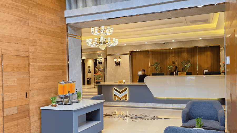 The corridor at the lobby of our hotel in New Delhi featuring the reception desk in the front with the receptionists standing behind the desk.