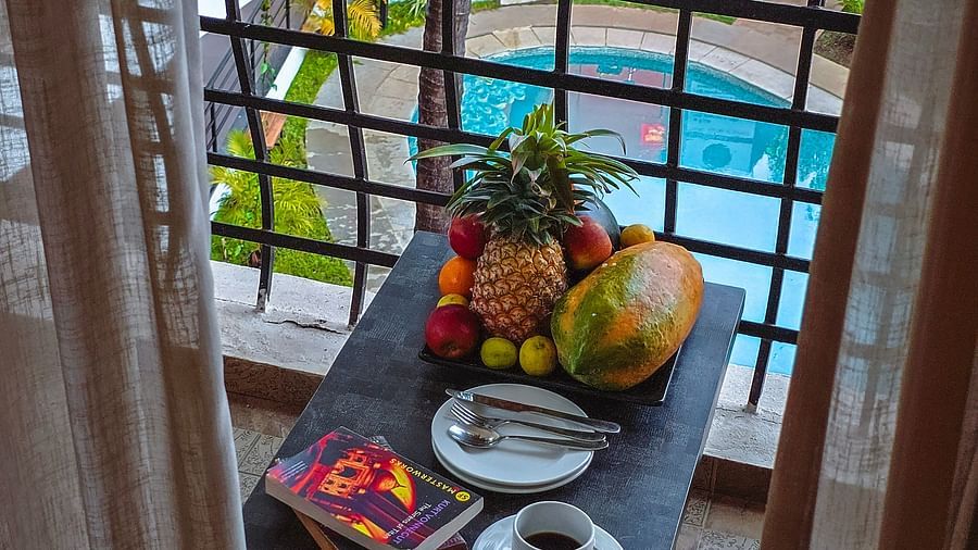 A balcony view with a fruit platter, beverages, and a pool in the background – The Verda de Miranda Resort.