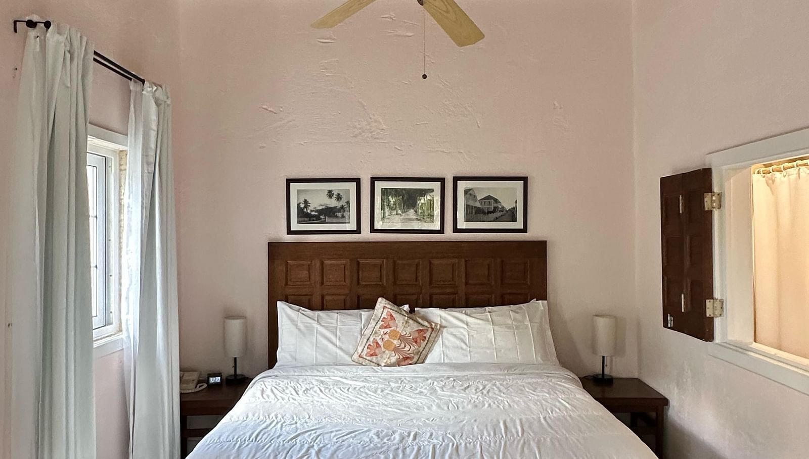 A bedroom with a bed covered in white linens and dark wooden floors | A Stone's Throw Away