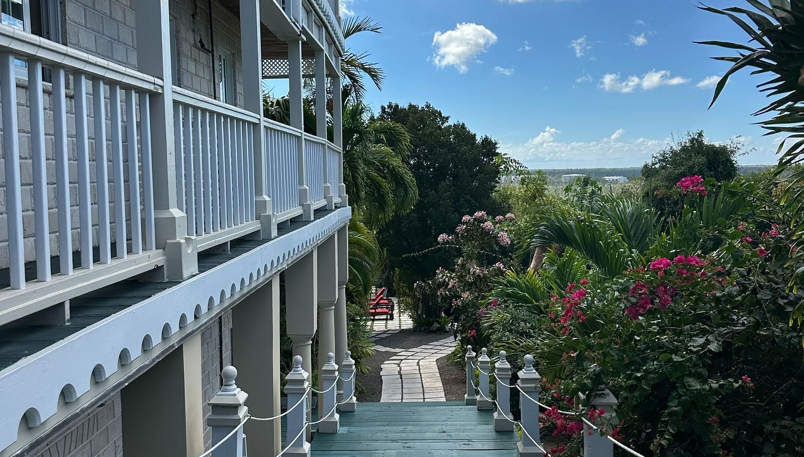 Exterior corridor with white railings and garden path below | A Stone's Throw Away
