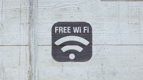 A stencilled sign of FREE Wi-Fi on a textured concrete wall.