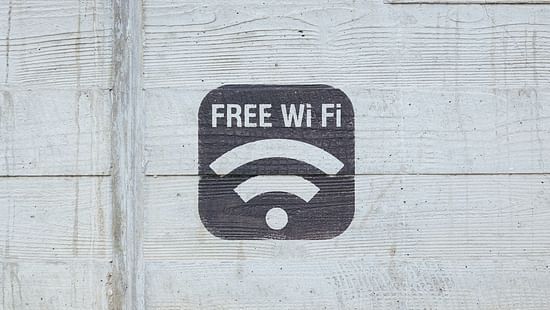 A stencilled sign of FREE Wi-Fi on a textured concrete wall.