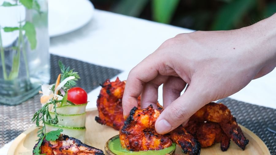 A person dipping Tandoori Prawns in a bowl of chutney | Mango Hill, Pondicherry
