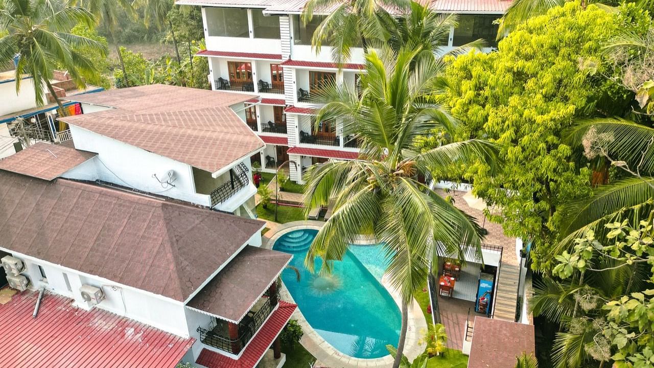 An aerial view of the The Verda de Miranda Resort nestled amidst palm trees, featuring multiple buildings and a turquoise pool.