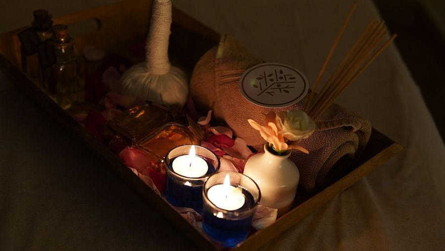 A pair of candles placed alongside some essential oils and towels on a tray in a spa