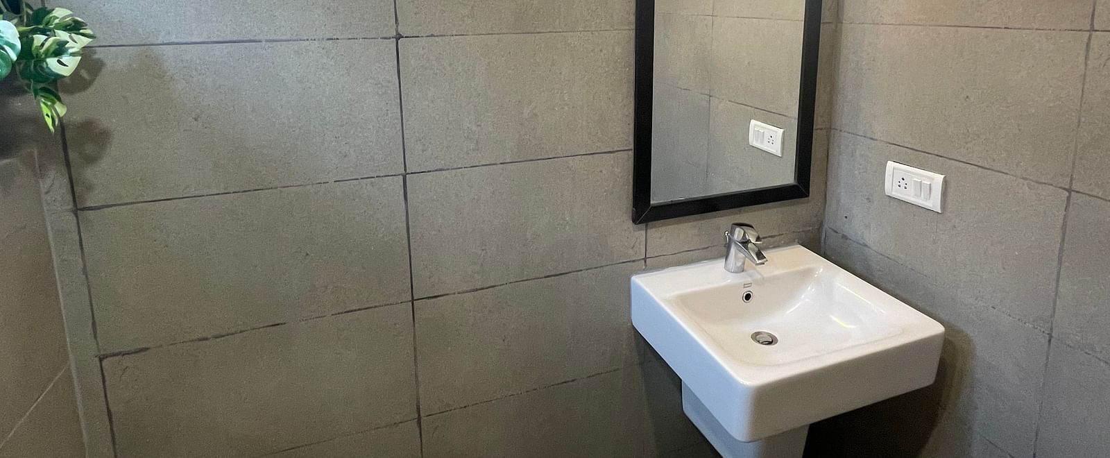 A washbasin and mirror mounted on the wall of a washroom at Sanctum Suites Richmond Road, Bangalore