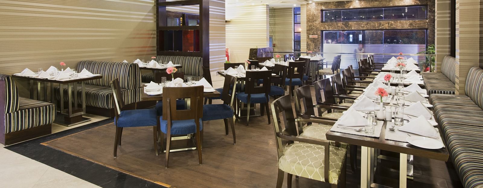 A closed dining space at The Manor Bareilly featuring multiple wooden tables and chairs arranged for a dining experience