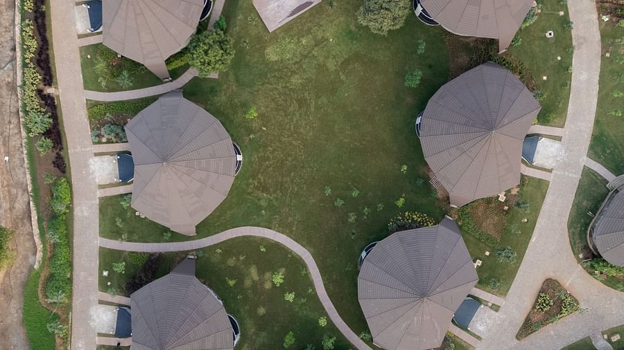 An aerial view of a property with hut style villas and  a huge lawn in the middle 