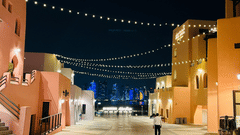An overview of an open cobbled road with many buildings on either side and a person walking in Gewan Island, Doha.
