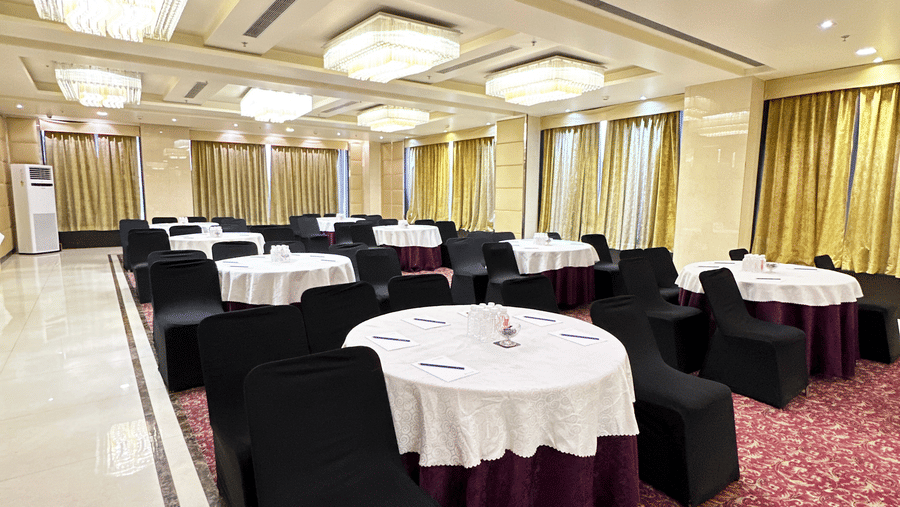 Royal Ballroom Hall 2 with neatly arranged & clothed round tables with cloth-covered chairs placed around them facing the podium.