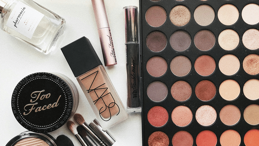 Beauty cosmetic products arranged on a table, featuring brushes and a vibrant color palette