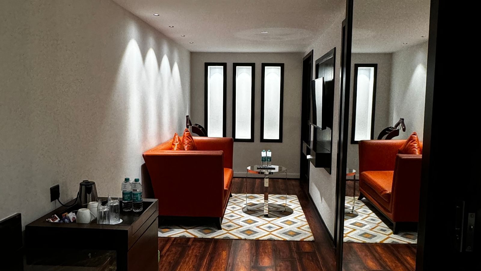 A stylish living area with a mirrored wall reflecting armchairs and a table at Cenneys Gateway.