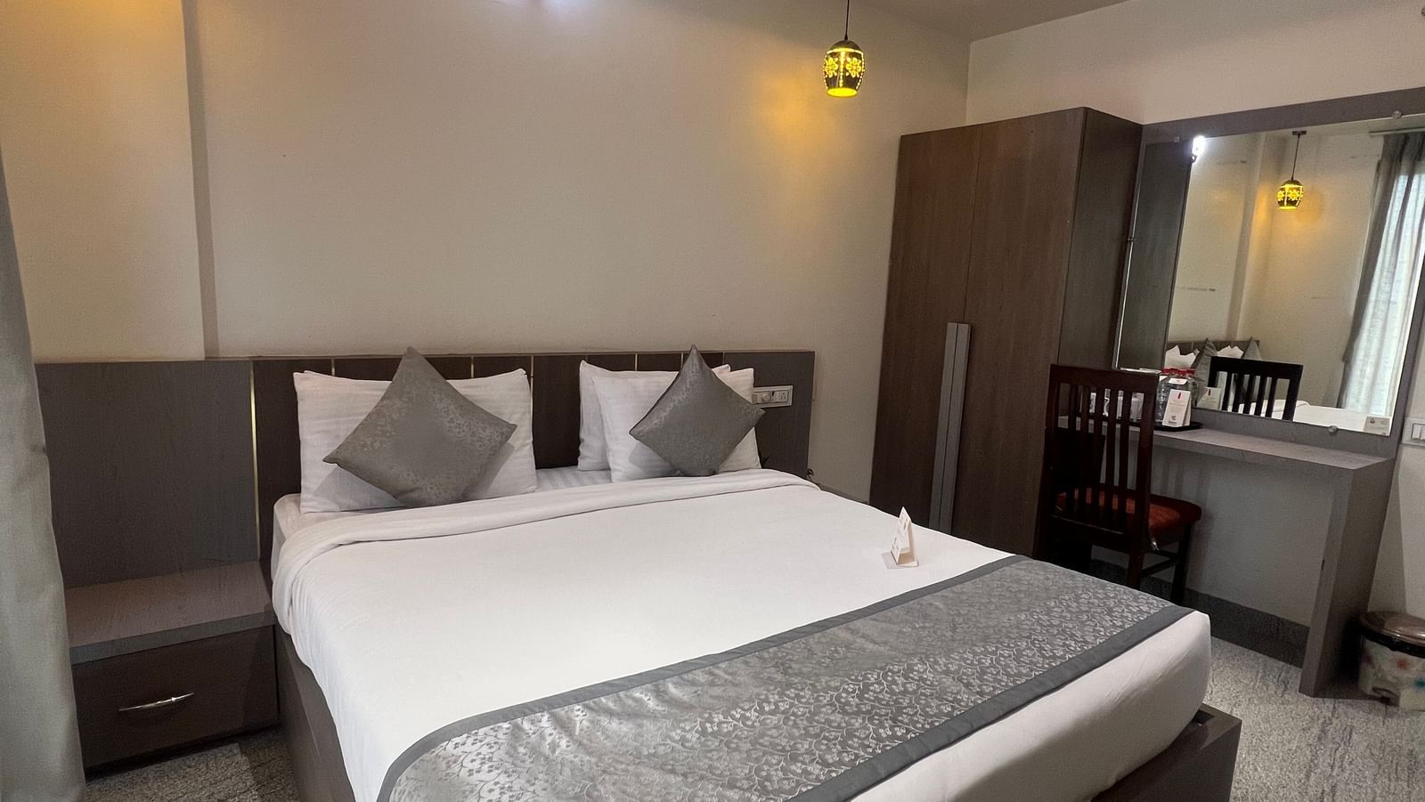 Queen size bed, wardrobe, as seen from the foot of the bed, in the Daksh Bliss room at Daksh The Valley Resort, Saputara.