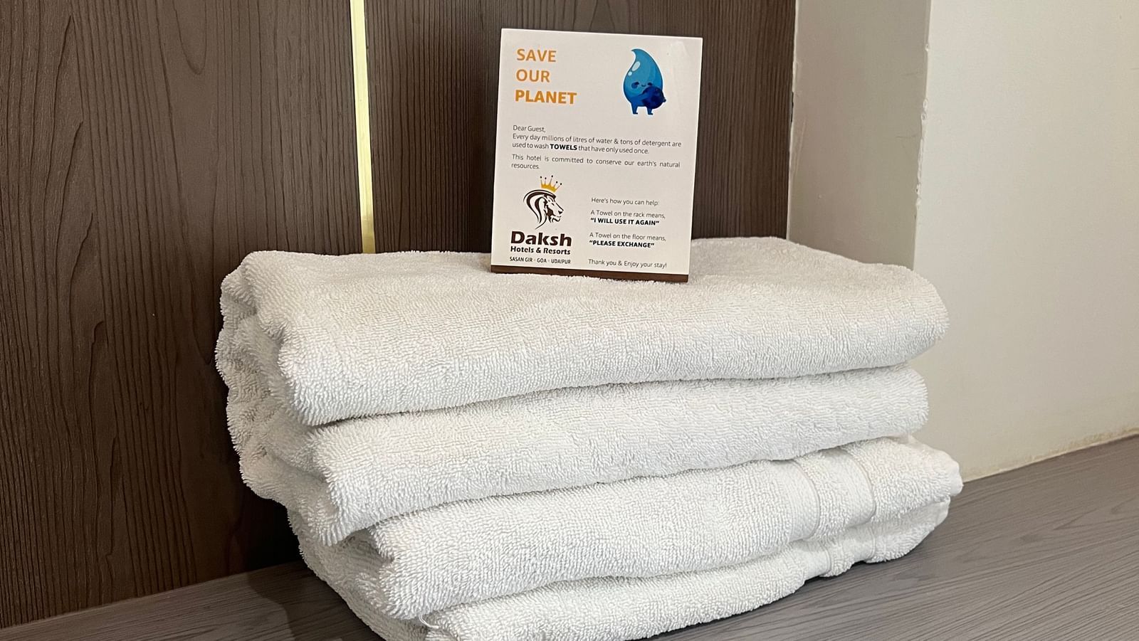 A bunch of folded towels placed on top of eachother on a wooden surface in the Daksh Bliss room at Daksh The Valley Resort, Saputara.