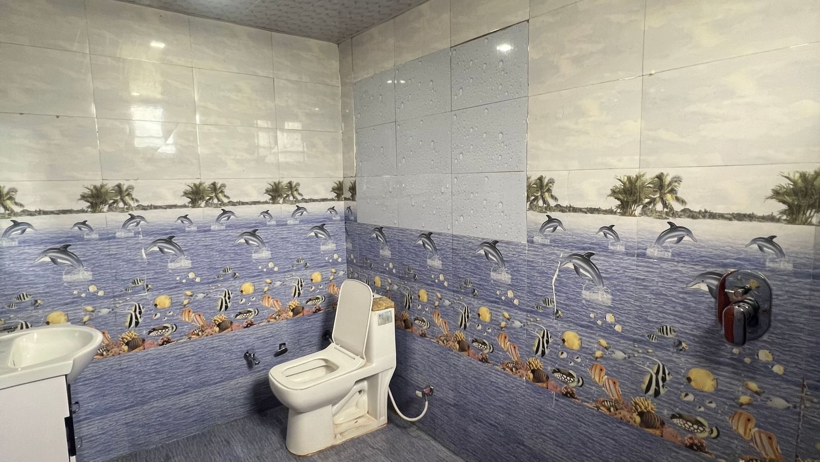 Bathroom of Daksh Elite Cottages furnished with a western commode, bathroom fittings, and a sink, at Daksh The Valley Resort, Saputara.