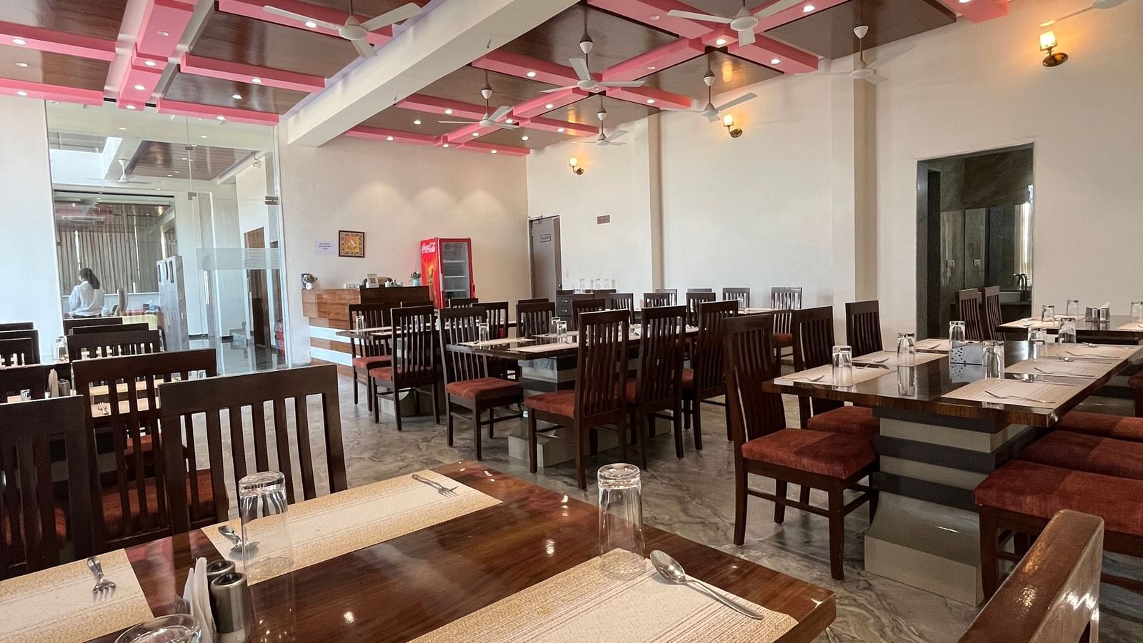 Corner view of the fine-dining restaurant at Daksh The Valley Resort, Saputara, furnished with neatly arranged dining tables, and warm overhead lighting.