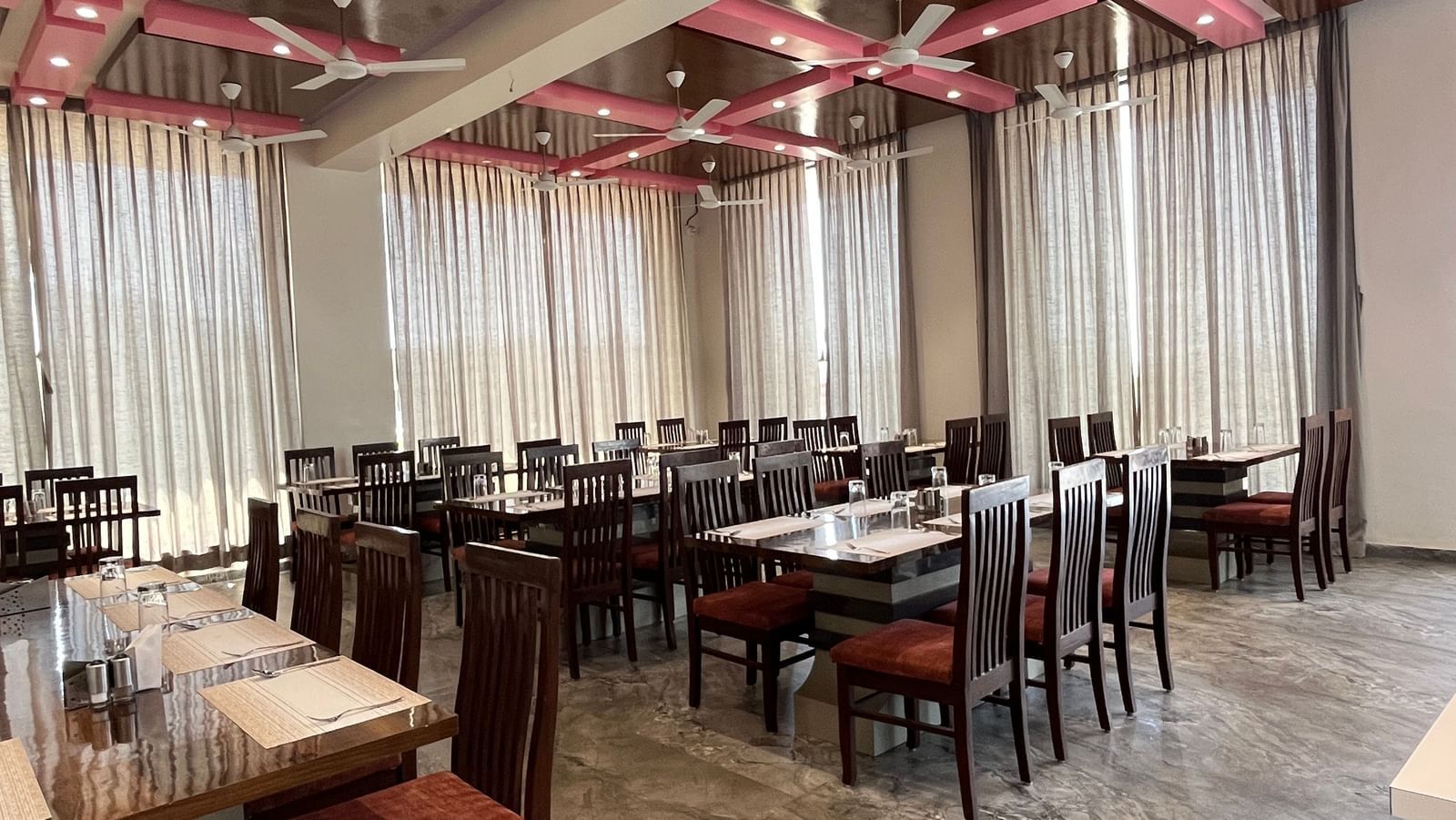 Extended view of the spacious and neatly arranged tables in the fine-dining restaurant at Daksh The Valley Resort, Saputara.