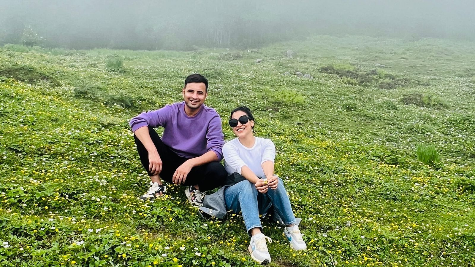 Image of a couple sitting on green grass at Garson Meadow | Faraway Cottages, Auli