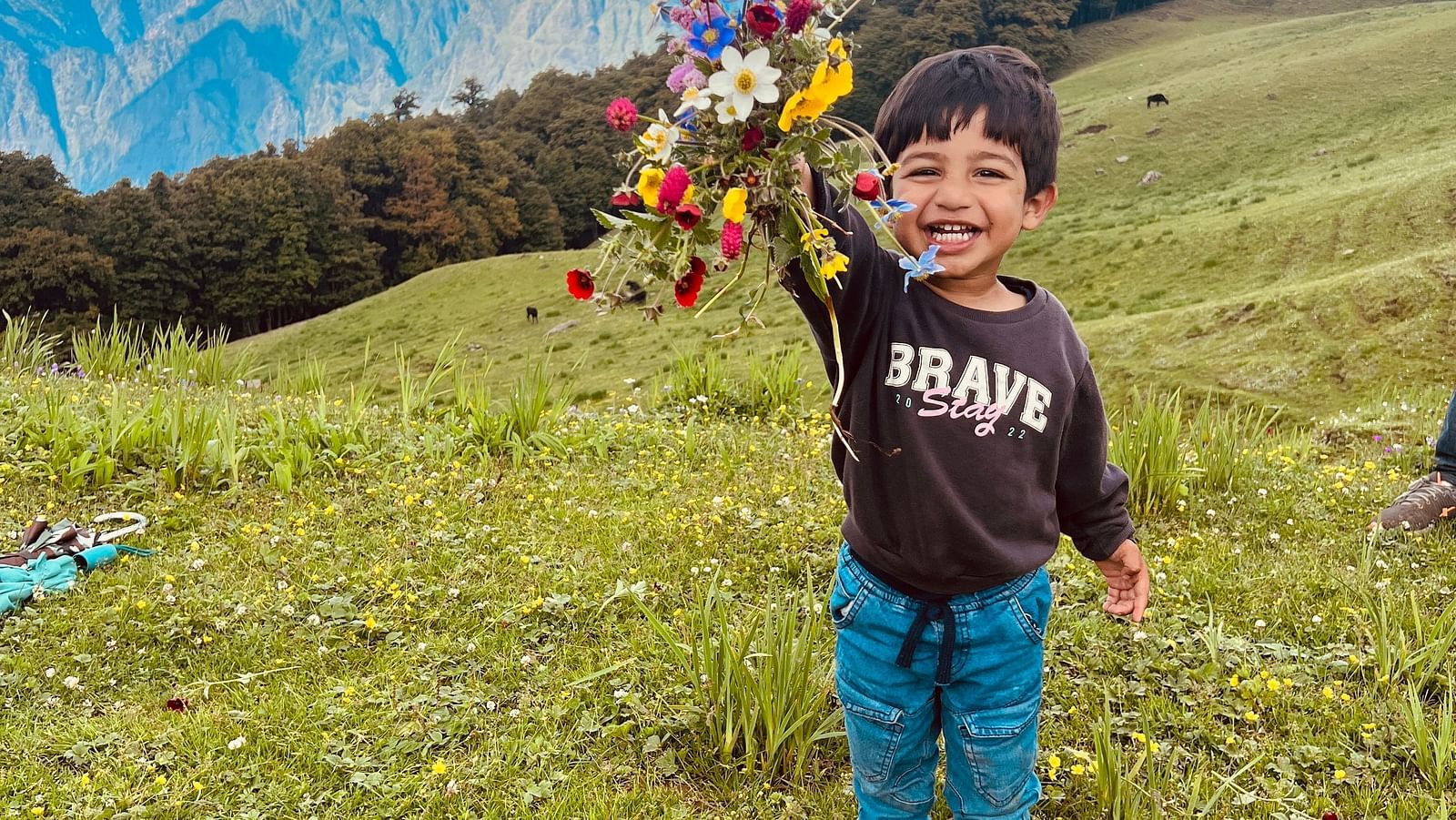 Image of a child holding up a bunch of flowers at Garson Meadow | Faraway Cottages, Auli