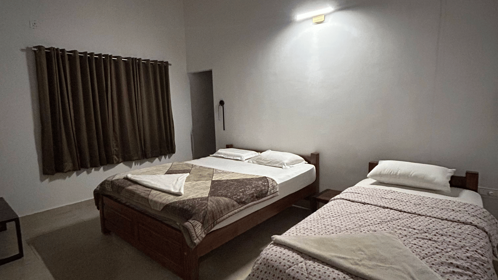 Hatti Eden Coorg | A bedroom with twin beds, and windows covered with curtains.