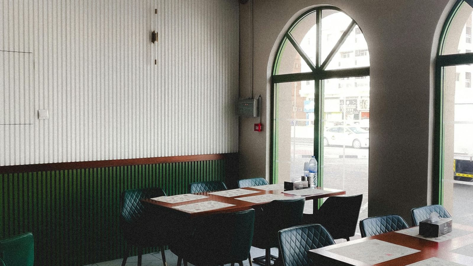 A small cafe interior with arched windows, simple tables, and chairs.