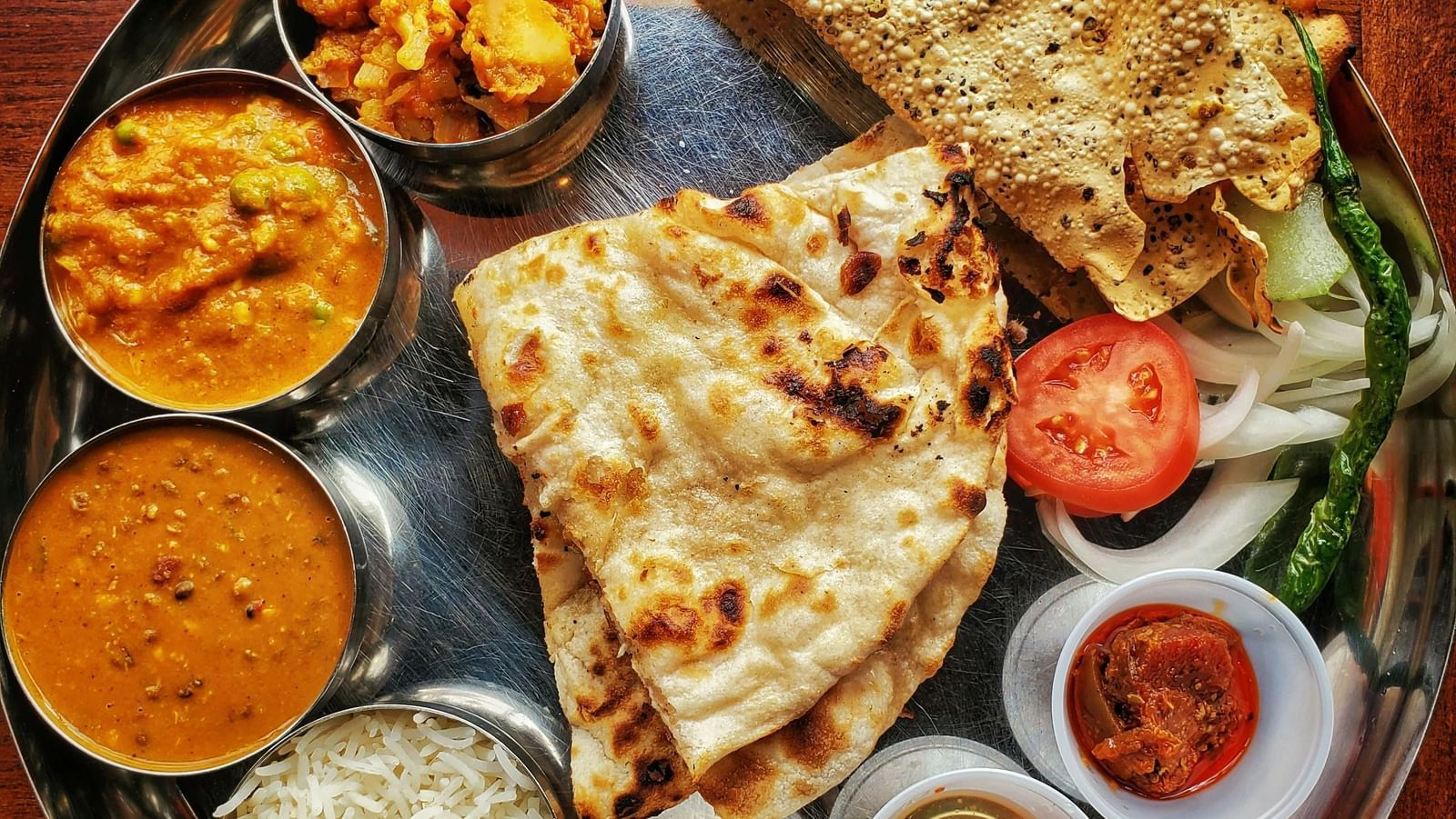A neatly arranged plate with several Indian delicacies served.