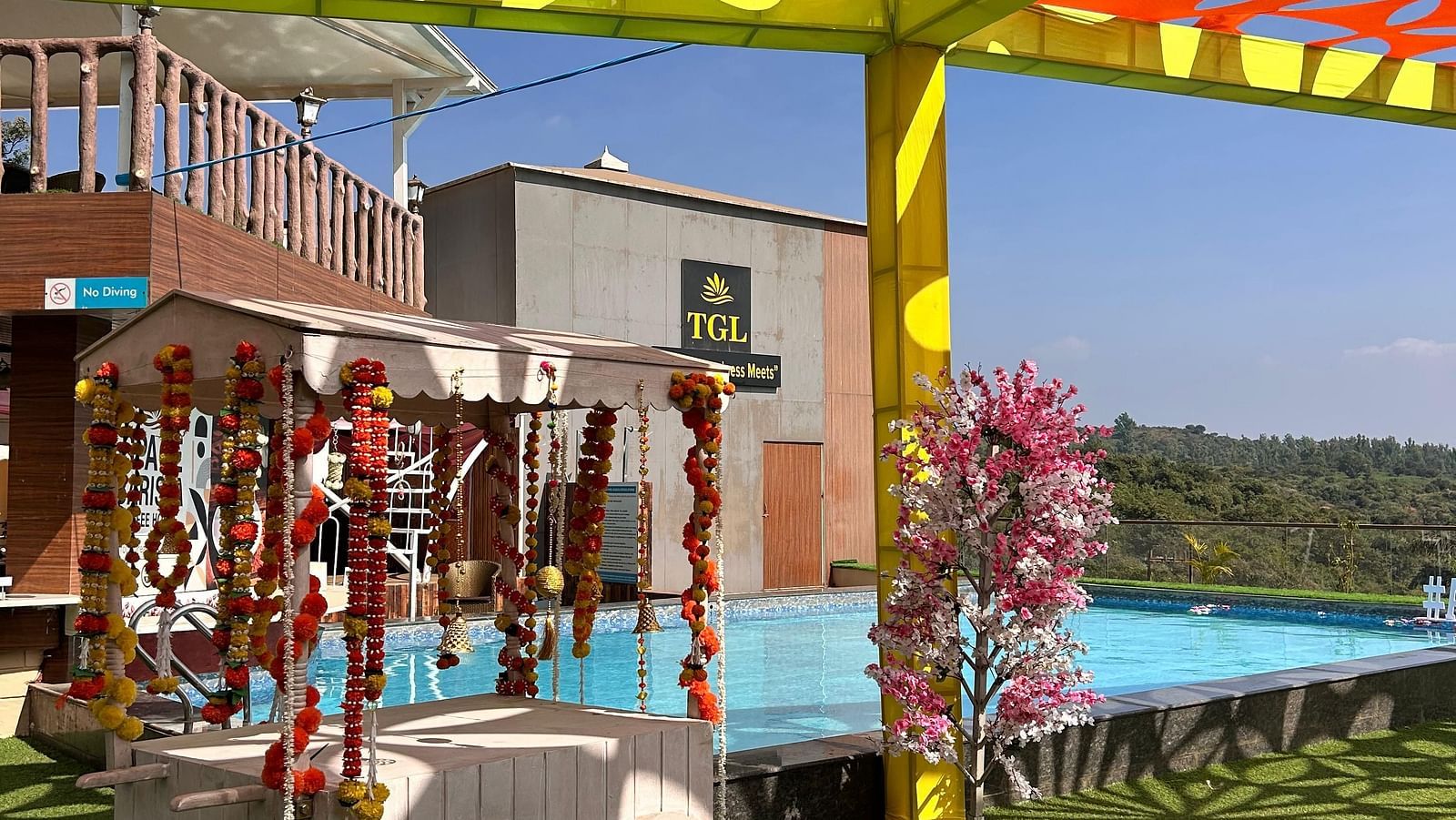 A carnival theme decorated area near swimming pool at The Grand Legacy Resort & Spa featuring a cart with wheels which is decorated with flowers and there are pillars around supporting cut out fabric page design - The Grand Legacy Resort & Spa