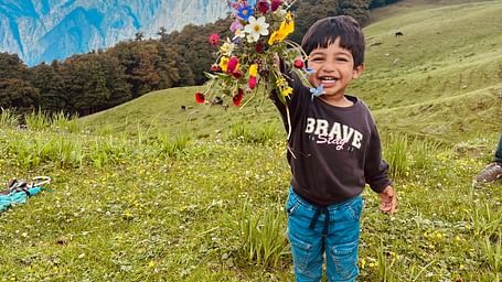 Image of a child holding up a bunch of flowers at Garson Meadow | Faraway Cottages, Auli