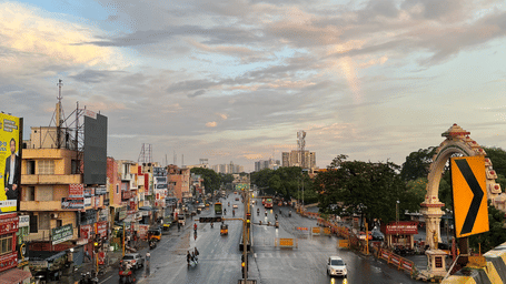 High-angle view of a wet city highway road with yellow and black barricades under a cloudy sky.