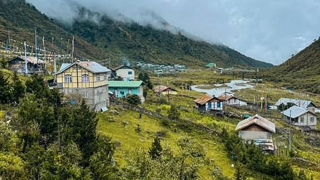 A lush green grassland with small colourful huts scattered around.